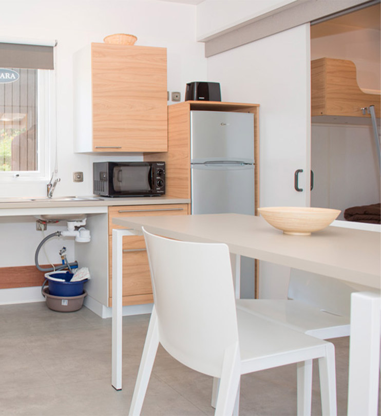 Cuisine avec réfrigérateur, micro-ondes, table et chaises