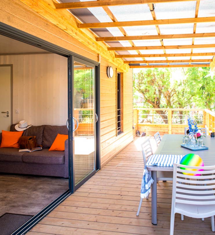 Terrasse couverte en bois avec mobilier de jardin moderne donnant sur le salon par une grande baie vitrée