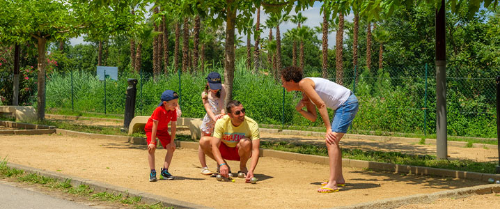 Parents apprenant aux enfants à jouer à la pétanque sur le boulodrome du camping